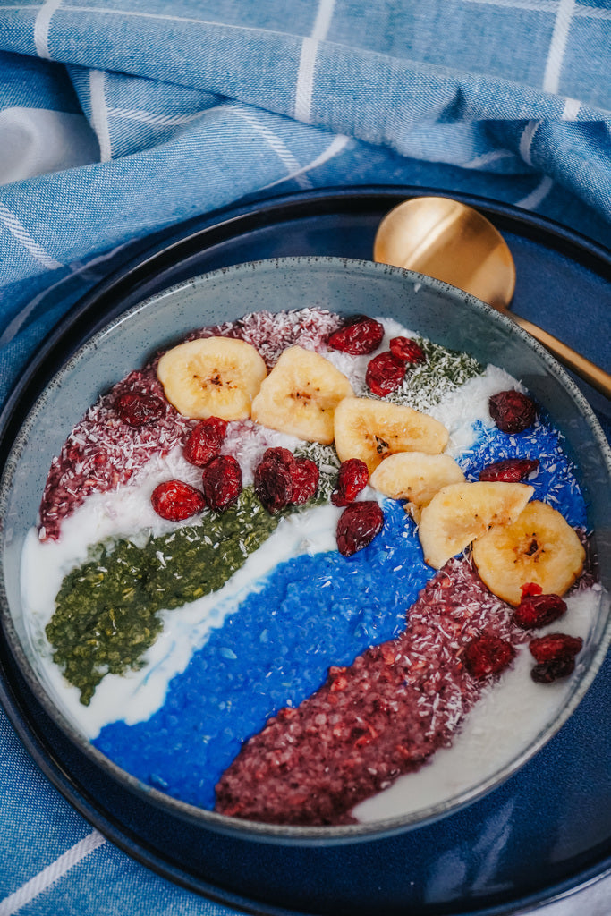 Smoothie bowl with blue spirulina, chlorella, berries, banana chips, and coconut flakes