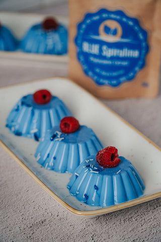 Panakota su mėlynąja spirulina stiklinėse, papuošta uogomis