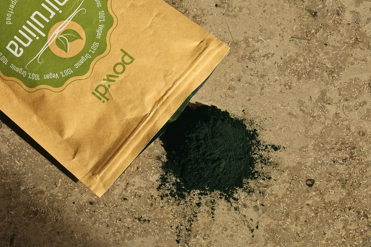 Powdi spirulinos milteliai su pakuote ant akmens