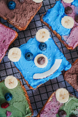 Colorful superfood toast with natural spreads, fruit toppings, and spirulina powder, on rack